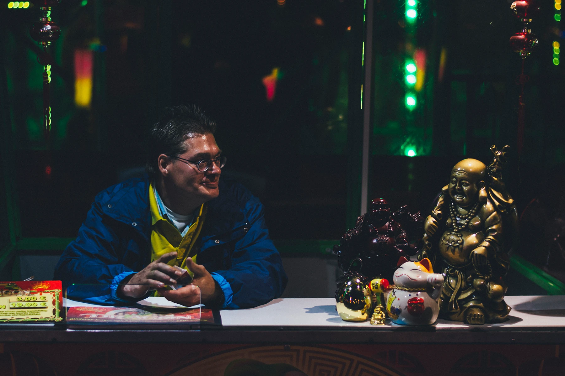 Photo of someone working at the Tilburgse Kermis with a buddha statue next to him.