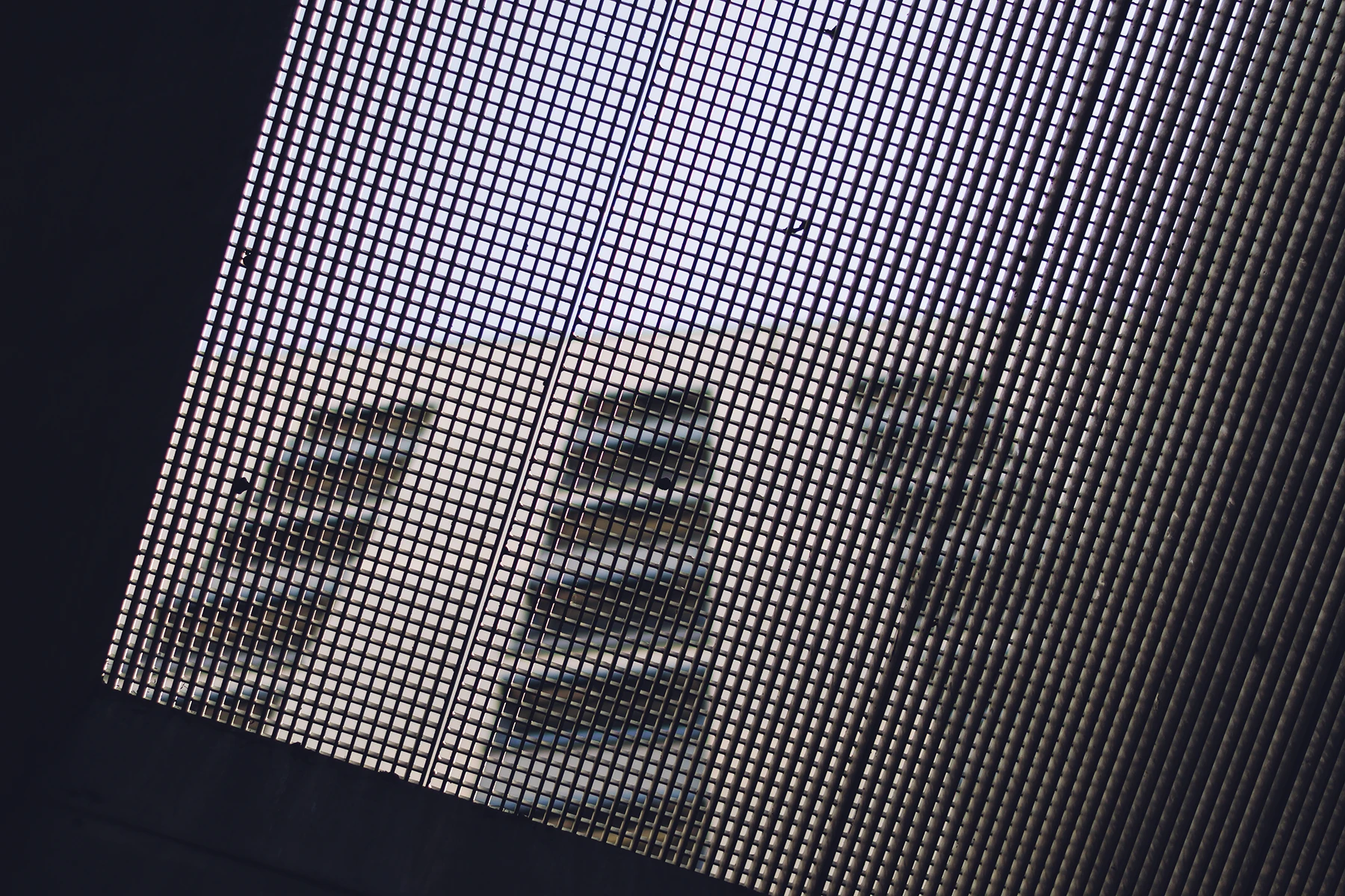 Photo of a building. But looking up. Behind a fence thing.