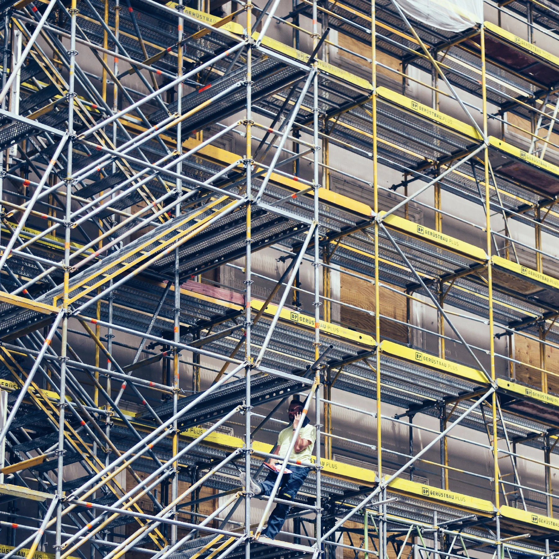 Another photo of scafolding. This time yellow. With a man calling inside it.